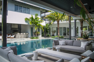 Inspiration for a mid-sized modern backyard rectangular infinity pool in Miami with a hot tub and concrete pavers.