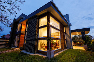 Photo of a mid-sized modern two-storey brown exterior in Sydney with wood siding and a flat roof.