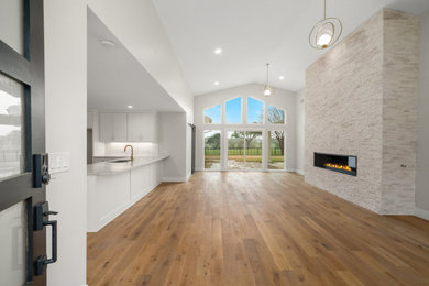 Inspiration for a 1950s medium tone wood floor, brown floor and vaulted ceiling living room remodel in Dallas with white walls, a stacked stone fireplace and a ribbon fireplace