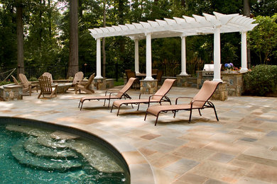 Patio - traditional stone patio idea in DC Metro with a pergola and a bbq area