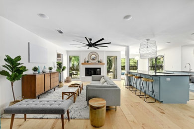 Transitional open concept light wood floor and beige floor living room photo in Austin with white walls, a standard fireplace and a brick fireplace