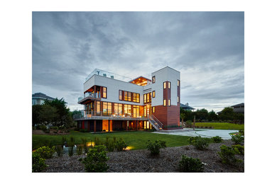 Inspiration for a large contemporary multicolored three-story mixed siding house exterior remodel in Other with a shed roof and a mixed material roof