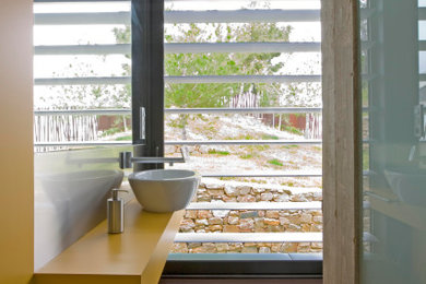 Ejemplo de cuarto de baño único y flotante actual de tamaño medio con puertas de armario amarillas, paredes amarillas, aseo y ducha, lavabo sobreencimera, suelo marrón y encimeras amarillas