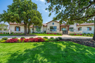 Large mediterranean gray one-story stone house exterior idea in Dallas with a hip roof and a tile roof
