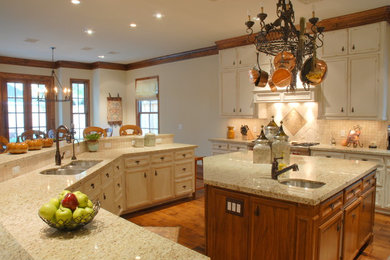 Kitchen - traditional medium tone wood floor kitchen idea in Houston with recessed-panel cabinets, distressed cabinets, granite countertops, beige backsplash, ceramic backsplash, stainless steel appliances and an island