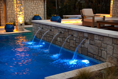 Photo of a large mediterranean backyard custom-shaped lap pool in Other with natural stone pavers and a water feature.