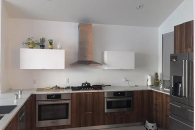Example of a mid-sized arts and crafts u-shaped porcelain tile and white floor eat-in kitchen design in New York with an undermount sink, flat-panel cabinets, dark wood cabinets, quartz countertops, white backsplash, stainless steel appliances, a peninsula and white countertops