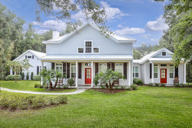Design ideas for a country two-storey white house exterior in Orlando with a gable roof and a metal roof.