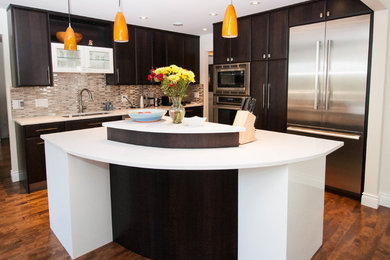 Eat-in kitchen - mid-sized contemporary l-shaped medium tone wood floor eat-in kitchen idea in Other with an undermount sink, flat-panel cabinets, dark wood cabinets, quartz countertops, gray backsplash, glass tile backsplash, stainless steel appliances and an island