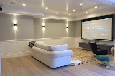 Photo of a large contemporary open concept home theatre in Other with grey walls, light hardwood floors, a projector screen and beige floor.
