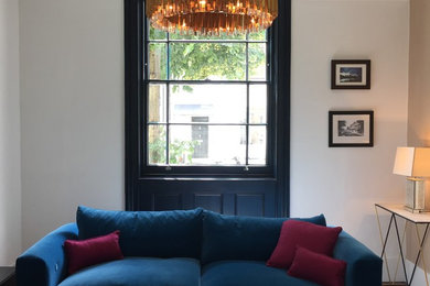 Medium sized contemporary enclosed living room in London with white walls, medium hardwood flooring, a standard fireplace and a metal fireplace surround.