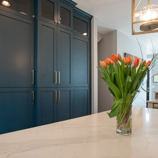 Inspiration for a mid-sized eclectic galley kitchen pantry in Denver with an undermount sink, shaker cabinets, turquoise cabinets, quartz benchtops, grey splashback, ceramic splashback, stainless steel appliances, light hardwood floors, with island, brown floor and white benchtop.