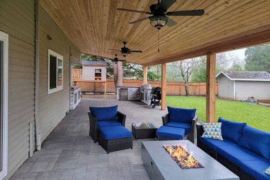 Inspiration for a large contemporary backyard concrete paver patio remodel in Portland with a fire pit and a roof extension