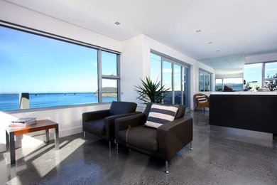 This is an example of a large modern open concept living room in Central Coast with beige walls and concrete floors.