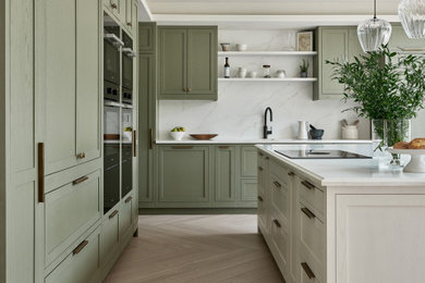 Inspiration for a mid-sized transitional l-shaped porcelain tile, beige floor and coffered ceiling open concept kitchen remodel in Hertfordshire with a drop-in sink, shaker cabinets, green cabinets, quartzite countertops, white backsplash, quartz backsplash, paneled appliances, an island and white countertops