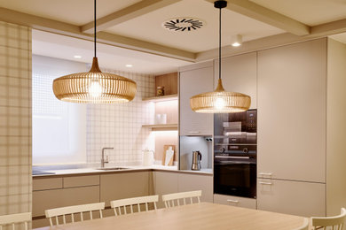 Foto de cocina blanca y madera clásica renovada de tamaño medio sin isla con fregadero bajoencimera, armarios con paneles lisos, puertas de armario beige, encimera de cuarzo compacto, electrodomésticos negros, suelo laminado, encimeras beige y casetón