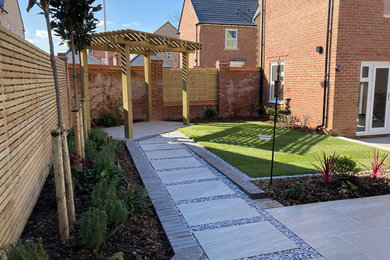 Design ideas for a medium sized contemporary back formal partial sun garden for summer in Essex with a pathway, decorative stones and a wood fence.