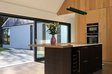 This is an example of a medium sized modern separated utility room in Dublin with flat-panel cabinets, medium wood cabinets and concrete flooring.