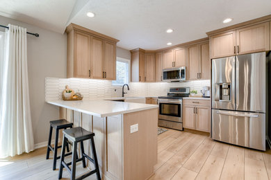 Kitchen pantry - cottage l-shaped laminate floor kitchen pantry idea in Other with a farmhouse sink, shaker cabinets, light wood cabinets, quartz countertops, white backsplash, subway tile backsplash, stainless steel appliances and white countertops