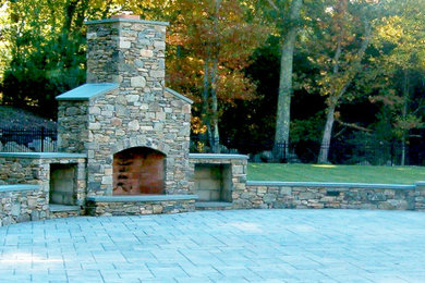 Example of a large classic backyard concrete paver patio design in Providence with a fireplace and no cover