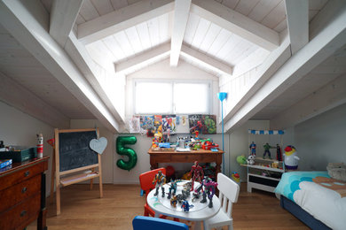 Immagine di un'In mansarda cameretta per bambini da 4 a 10 anni contemporanea di medie dimensioni con pareti bianche, pavimento in legno massello medio e travi a vista