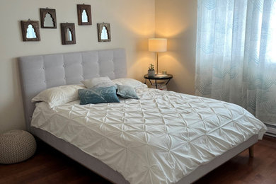Ejemplo de dormitorio principal costero de tamaño medio con paredes beige, suelo de madera en tonos medios, suelo marrón y papel pintado