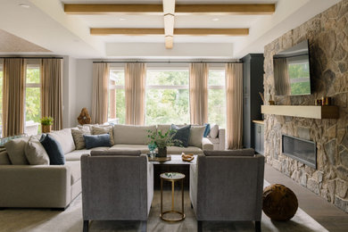 Example of a large medium tone wood floor, gray floor and exposed beam living room design with gray walls and a stone fireplace