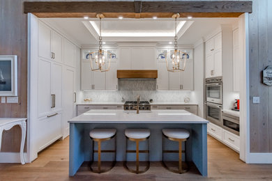 Inspiration for a small transitional u-shaped brown floor and tray ceiling eat-in kitchen remodel in Other with a farmhouse sink, recessed-panel cabinets, white cabinets, multicolored backsplash, stainless steel appliances, an island and white countertops