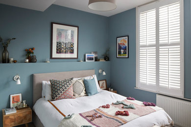 Imagen de dormitorio principal contemporáneo pequeño sin chimenea con paredes azules, moqueta y suelo gris