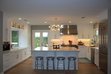 Kitchen - large coastal u-shaped light wood floor kitchen idea in San Diego with an undermount sink, shaker cabinets, white cabinets, marble countertops, white backsplash, ceramic backsplash, stainless steel appliances and an island