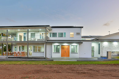 This is an example of a large contemporary two-storey grey exterior in Sunshine Coast with concrete fiberboard siding and a shed roof.