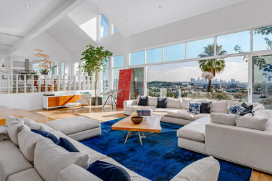 Expansive contemporary open concept living room in Los Angeles with white walls, medium hardwood floors and brown floor.