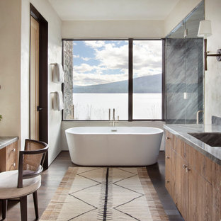 Example of a large mountain style master dark wood floor and brown floor bathroom design in Other with flat-panel cabinets, medium tone wood cabinets, an integrated sink, granite countertops, a hinged shower door, gray countertops and beige walls