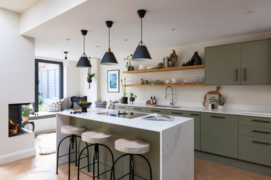 Imagen de cocina actual con armarios con paneles lisos, puertas de armario verdes, encimera de cuarcita, suelo de madera en tonos medios y encimeras blancas
