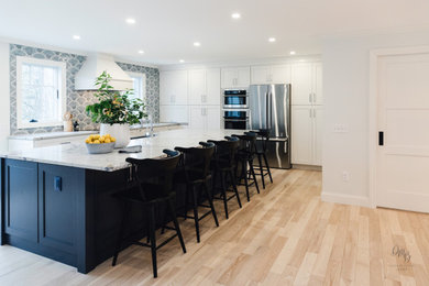 Inspiration for a transitional white floor and light wood floor kitchen remodel in Other with a farmhouse sink, flat-panel cabinets, blue cabinets, quartz countertops, blue backsplash, glass tile backsplash, stainless steel appliances, an island and white countertops