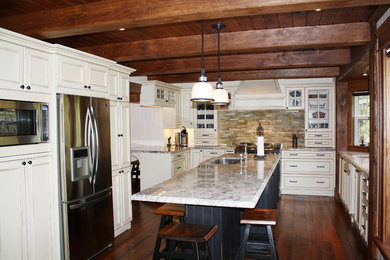 Large transitional u-shaped dark wood floor enclosed kitchen photo in Toronto with an undermount sink, beige cabinets, granite countertops, multicolored backsplash, stone tile backsplash, stainless steel appliances, an island and raised-panel cabinets