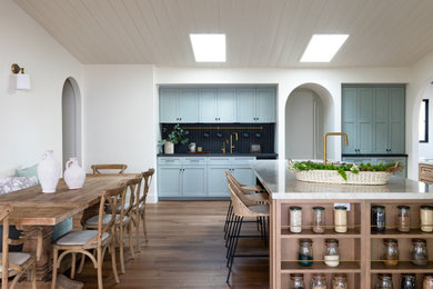Eat-in kitchen - coastal vaulted ceiling eat-in kitchen idea in San Diego with quartzite countertops, black backsplash and an island