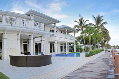 Inspiration for a large tropical beige two-story stucco house exterior remodel in Miami