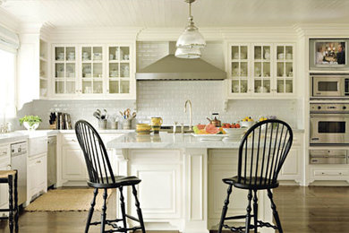 Example of a large trendy l-shaped medium tone wood floor eat-in kitchen design in Toronto with an undermount sink, glass-front cabinets, white cabinets, marble countertops, white backsplash, subway tile backsplash, stainless steel appliances and an island