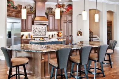Elegant l-shaped dark wood floor and brown floor eat-in kitchen photo in Orlando with an undermount sink, raised-panel cabinets, dark wood cabinets, granite countertops, beige backsplash, brick backsplash, stainless steel appliances and two islands