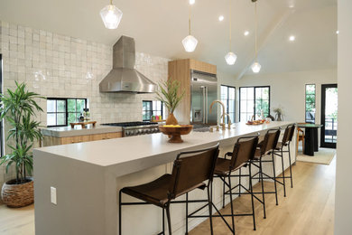 Example of a mid-sized trendy single-wall medium tone wood floor and brown floor eat-in kitchen design in Los Angeles with medium tone wood cabinets, quartz countertops, white backsplash, stainless steel appliances, an island and gray countertops