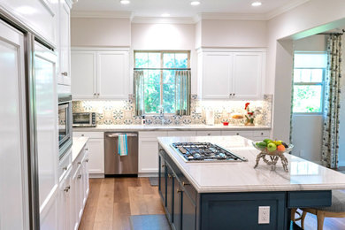 Design ideas for a traditional eat-in kitchen in Orange County with a single-bowl sink, recessed-panel cabinets, quartz benchtops, blue splashback, porcelain splashback, stainless steel appliances, vinyl floors, with island, brown floor and white benchtop.