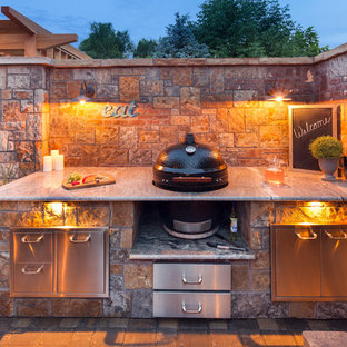 This is an example of a mid-sized country backyard patio in Denver with a fire feature, brick pavers and no cover.