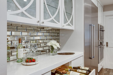 Inspiration for a mid-sized transitional single-wall medium tone wood floor and brown floor wet bar remodel in Sacramento with an undermount sink, flat-panel cabinets, white cabinets, solid surface countertops, mirror backsplash and white countertops