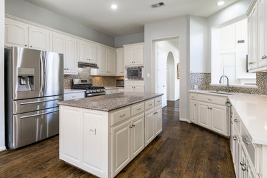 Example of a large transitional dark wood floor and brown floor eat-in kitchen design in Dallas with an undermount sink, raised-panel cabinets, white cabinets, quartz countertops, gray backsplash, glass tile backsplash, stainless steel appliances, an island and white countertops