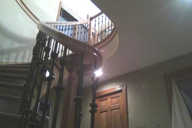 Ejemplo de escalera curva tradicional grande con escalones de madera y contrahuellas de madera