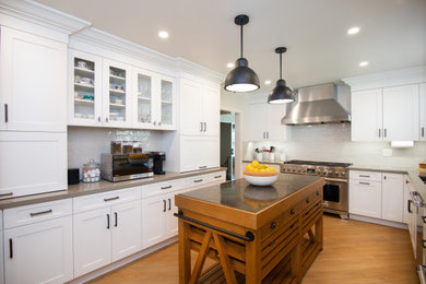 Mid-sized elegant l-shaped enclosed kitchen photo in Los Angeles with an undermount sink, shaker cabinets, white cabinets, quartz countertops, white backsplash, ceramic backsplash, stainless steel appliances, an island and gray countertops