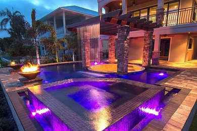 Mid-sized transitional backyard stamped concrete and custom-shaped hot tub photo in Tampa