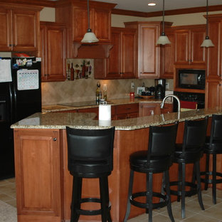 Mid-sized traditional kitchen pantry ideas - Inspiration for a mid-sized timeless l-shaped kitchen pantry remodel in Louisville with an undermount sink, raised-panel cabinets, medium tone wood cabinets, granite countertops, stone tile backsplash, black appliances and an island