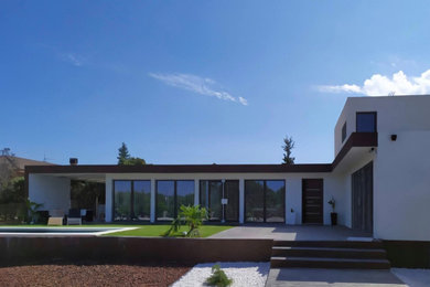 Ejemplo de fachada de casa blanca y gris minimalista grande de dos plantas con revestimientos combinados, tejado plano y tejado de varios materiales